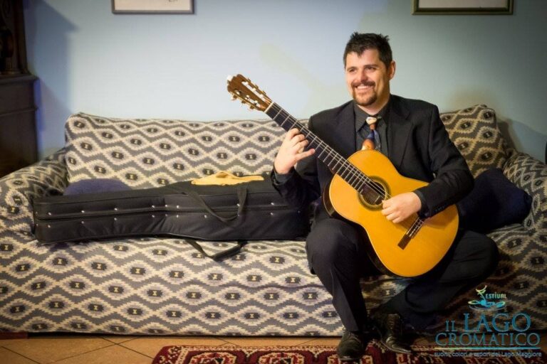 Marco Brusa seduto con la chitarra classica in un rifugio